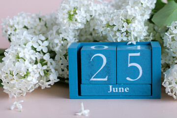 White lilac flowers and blue perpetual calendar showing june 25th