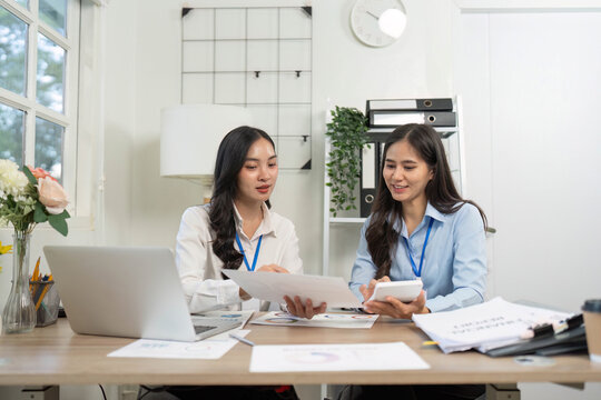 Collaboration in Finance. Two women discussing financial reports in modern office.