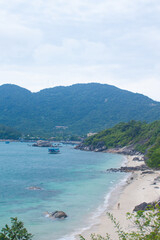 Obraz premium Scenic coastal view of Cham Islands with fishing boats, tropical mountains and a person walking along a deserted beach.