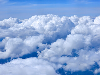 Naklejka premium White fluffy clouds in the upper atmosphere against a clear blue sky. Sky, peace concept. Quiet and calm atmosphere.