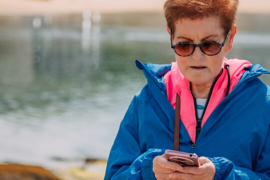 senior woman phone and beach in social media, communication or chatting in the outdoors. Senior female on ocean coast having a online conversation or texting on mobile smartphone