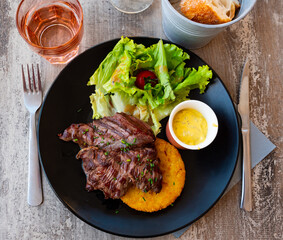 Onglet de bouef - traditional French meat dish with spices, lettuce, vegetables and cheese sauce