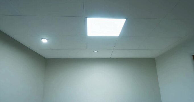 Simple meeting room with bright white lights switching on, an empty table, and clean walls