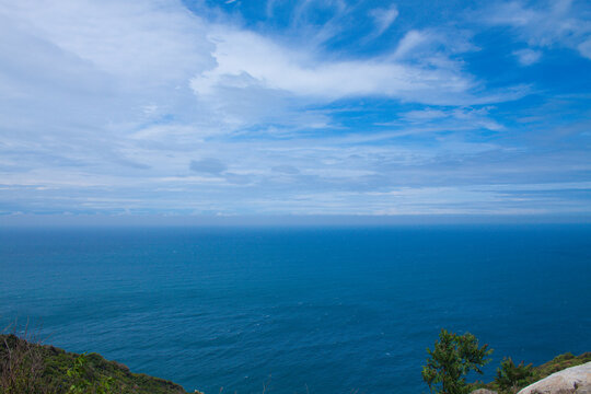Minimal seascape with calm blue ocean stretching into the distance beneath a soft cloudy sky. 