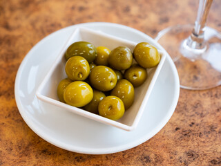 White plate with delicious green olives with pits