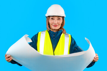 Construction worker holds blueprint in bright blue background while working on a project at a...