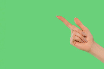 Hand pointing towards a green background with a clear intention of directing attention or...