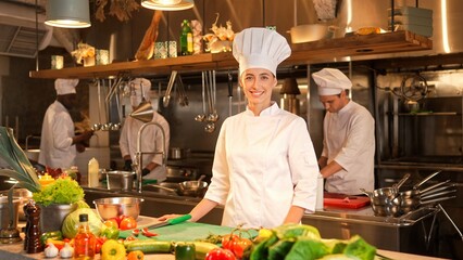 Portrait of professional caucasian female chef posing in kitchen of fancy restaurant looking at...