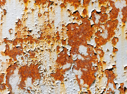 A rusty wall with white paint peeling off