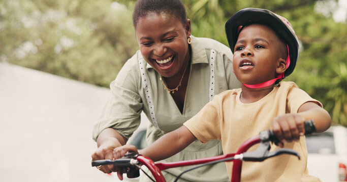 Support, teaching and boy on bicycle with mom on street of neighborhood for child development. African woman, smile or black kid with trust, help or single mother to learn how to ride bike outside
