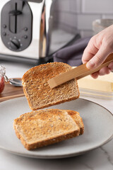 Freshly toasted bread being picked up with wooden tongs. Frontal scene focusing on the serving...