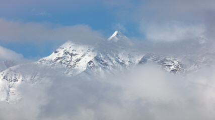 Obraz premium A mountain covered in snow with a cloudy sky in the background