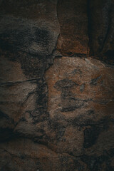 Dark textured rock surface with natural cracks and mineral patterns. Perfect for use as a background, texture, or design element.
