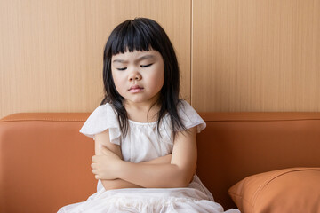 A sad little Chinese girl on the sofa
