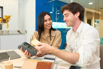 Obraz premium Couple paying with credit card for interior design project in furniture showroom