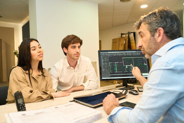Architect showing blueprint to couple designing home interior in furniture showroom
