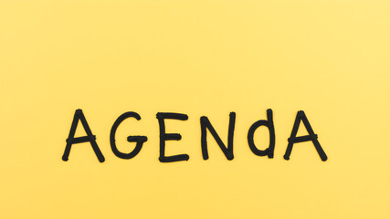 Agenda word on yellow background with copy space for text.
