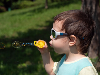 boy blowing bubbles, child wearing sunglasses for kids, soap bubbles