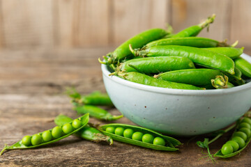 Fresh green pea pods with green peas on a wooden background. Sweet green peas. Green pea beans vegetables. Vegan. healthy vegetable. Copy space