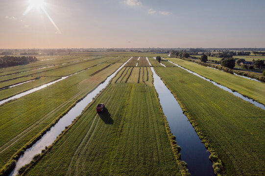 Typical Dutch polder landscape with a farmer driving a truck through his field.