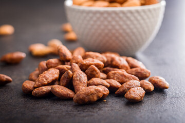Nuts coated in sugar and honey on black table.