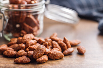 Almond nuts coated in sugar and honey on wooden table.