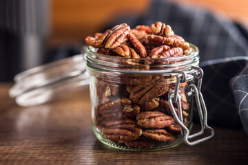 Peeled pecan nuts in jar on wooden table.