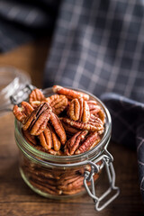 Peeled pecan nuts in jar on wooden table.