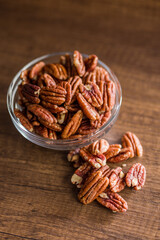 Peeled pecan nuts in bowl on wooden table.