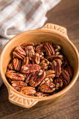 Peeled pecan nuts in bowl on wooden table.