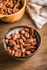 Nuts coated in sugar and honey in bowl on wooden table.