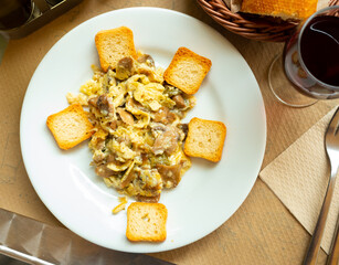 Fried eggs with mushrooms and spring garlic served with crispy croutons. Catalan cuisine. Dinner with glass of wine.