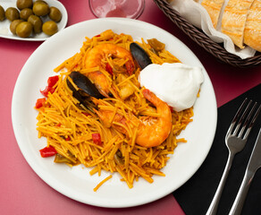 Appetizing pasta paella fideua with seafood served on platter