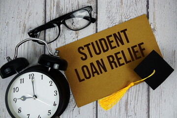 Student Loan Relief text on paper card with alarm clock top view on wooden background