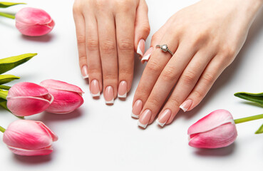 Woman showing french manicure near pink tulips on white background