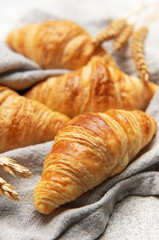 Freshly baked croissants resting on a linen cloth with wheat stalks