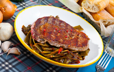Appetizing roasted beef steak with braised green beans and bell pepper on white plate