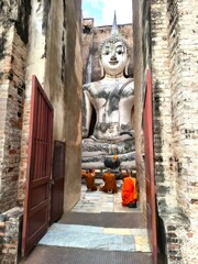 Serene Buddha Statue Surrounded by Monks in Ancient Temple Ruins