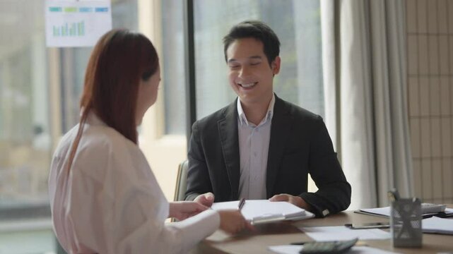 Two business associates close a deal by signing the final agreement in a company conference room