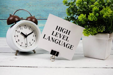 High-Level Language text written on paper card with alarm clock on wooden background