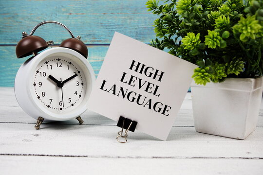 High-Level Language text written on paper card with alarm clock on wooden background