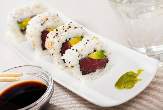 Uramaki sushi rolls with raw tuna and avocado inside, decorated with sesame seeds