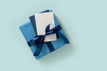 Happy Fathers Day concept with blue gift box and blank on pastel blue background. Flat lay. View from above. Copy space.