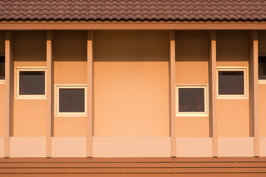 Beige building with brown tile roof and abstract geometric pattern of shading fins and square tinted glass windows on concrete house wall surface. Vintage home exterior architecture background - Powered by Adobe