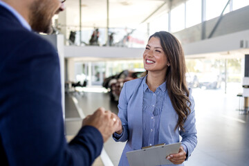 Confident sales team in dealership, two beautiful consultants or managers in black full suit with...