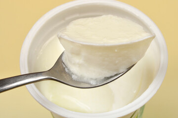 A close-up, eye-level shot captures a spoonful of thick white yogurt overflowing, just lifted from...