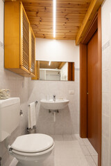 Renovated modern bathroom interior in an old, typically Italian building with a wooden ceiling.