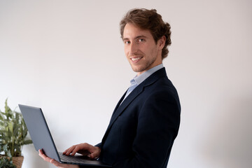 Smiling businessman using his laptop in a bright office.