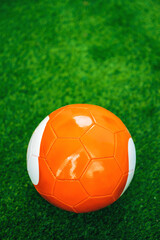 Orange soccer ball on artificial grass pitch