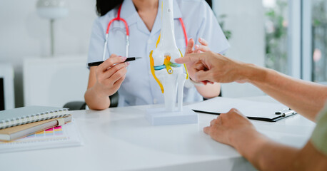 Orthopedic surgeon shows knee model to patient in human knee hospital. Knee joint diseases and...